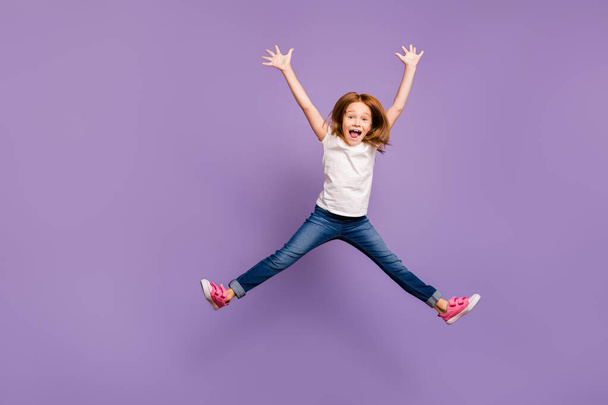 Full length photo of funny small foxy lady jumping high rejoicing making star shape in air cheerful crazy mood wear casual t-shirt jeans isolated purple background - Photo, image