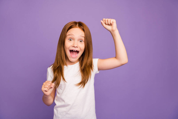 Photo of pretty excited little foxy lady raising fists screaming loudly got best examination grade results celebrating wear white t-shirt isolated purple background - Фото, изображение