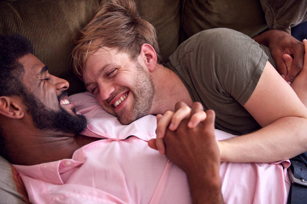 Aimer mâle gay couple relaxant couché sur canapé à la maison étreinte
 - Photo, image