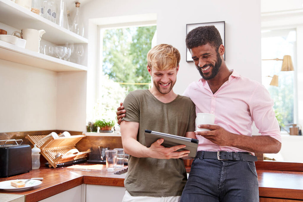 Male Gay Couple Using Digital Tablet At Home In Kitchen Together - Foto, imagen