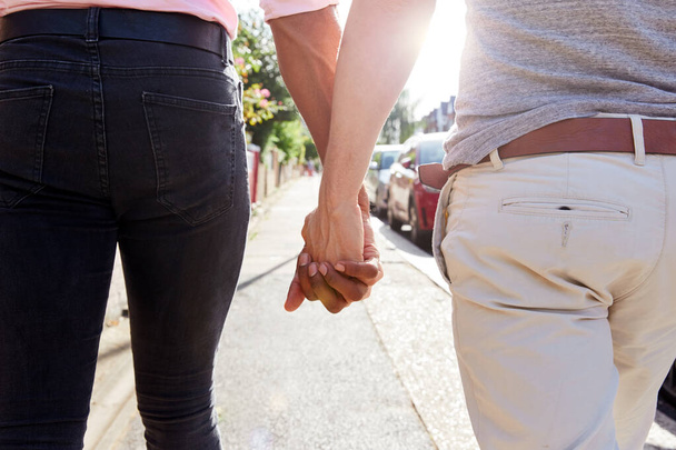 Close Up View Of Same Sex Male Couple Holding Hands As They Walk Along Road From Behind - Foto, afbeelding