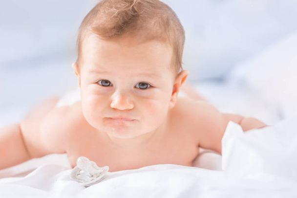 Portrait of cute toddler boy lying on bed. Newborn child in bedr - Photo, Image