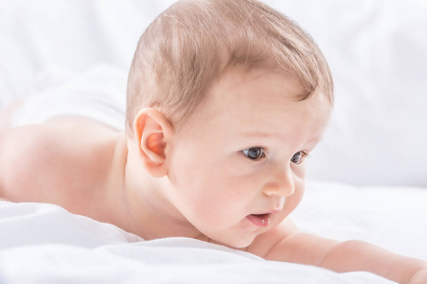 Portrait of cute toddler boy lying on bed. Newborn child in bedr - Fotó, kép