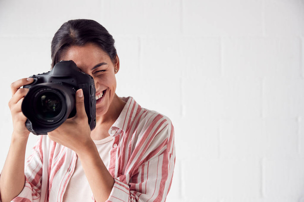 Female Photographer With Camera On Photo Shoot Against White Stu - Foto, imagen