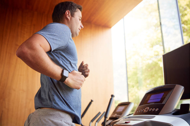 Man Exercising On Treadmill At Home Wearing Smart Watch - Foto, Imagen