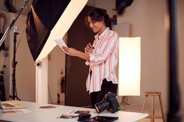 Female Photographer Editing Images From Photo Shoot In Studio - 写真・画像