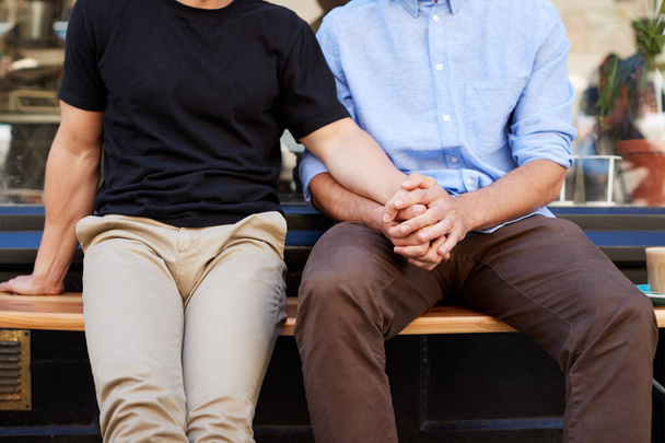 Close Up Of Male Gay Couple Sitting Outside Coffee Shop Holding Hands - Foto, immagini
