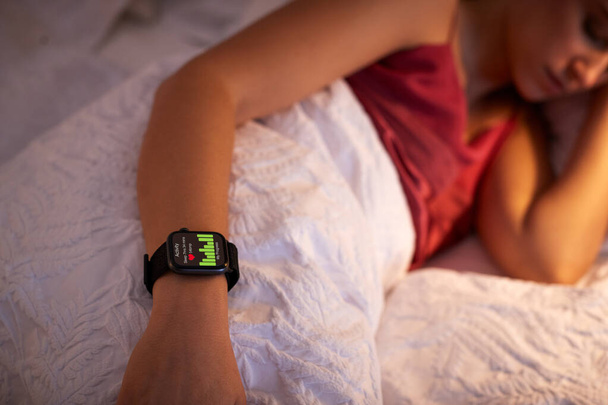 Woman Sleeping In Bed With Focus On Smart Watch She Is Wearing - Foto, afbeelding