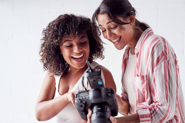 Smiling Female Photographer Holding Camera With Model In Studio  - Foto, imagen