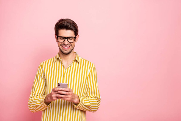 Photo of handsome guy typing girlfriend sms holding telephone social addicted person wear specs hipster striped shirt isolated pink color background - Фото, зображення