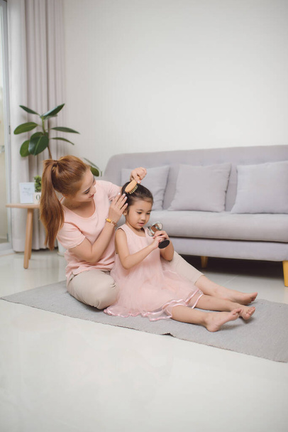 Una joven madre peinando un pelo niña
 - Foto, Imagen