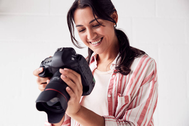 Female Photographer With Camera On Photo Shoot Against White Stu - Foto, imagen