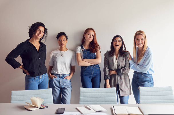 Portrait Of Young Female Business Team Standing By Table In Meeting Room In Modern Workspace - Foto, afbeelding