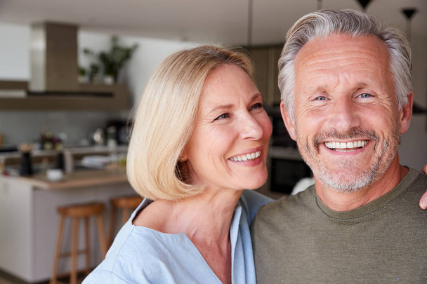 Portrait Of Smiling Senior Couple Standing At Home In Kitchen Together - Fotó, kép
