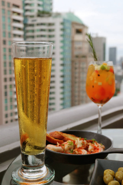 Sklenice chlazeného točeného piva s rozmazaným čerstvým ovocem Sangria koktejl a Tapas na střešní terase - Fotografie, Obrázek