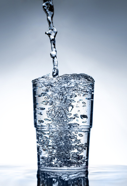 Sauberes Glas auf Wasser stehend mit Flüssigkeit - Foto, Bild
