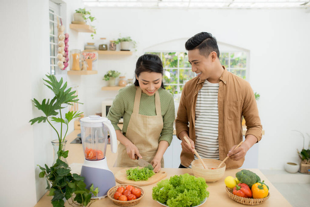 Portrait of happy young Asian couple cooking together in the kitchen at home. - Foto, Imagen
