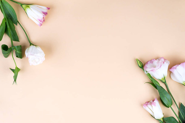 Frame compositie met lege ruimte in het centrum gemaakt van bloeiende roze eustoma, platte lay. Bloemen decoratieve hoeken op beige achtergrond. - Foto, afbeelding