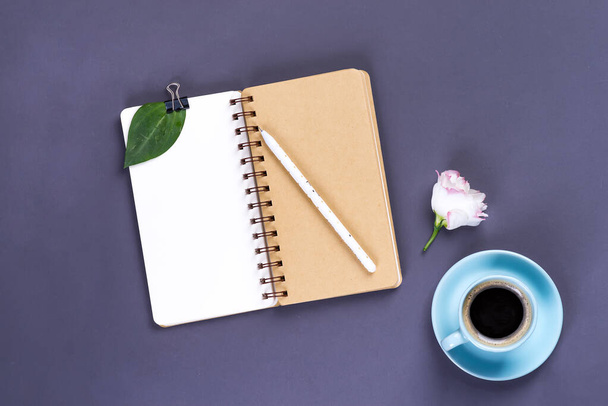 朝のコーヒーマグカップ、空のノートブック、鉛筆、暗いテーブルの上の白い花、居心地の良い朝食、トップビュー、コピースペース - 写真・画像