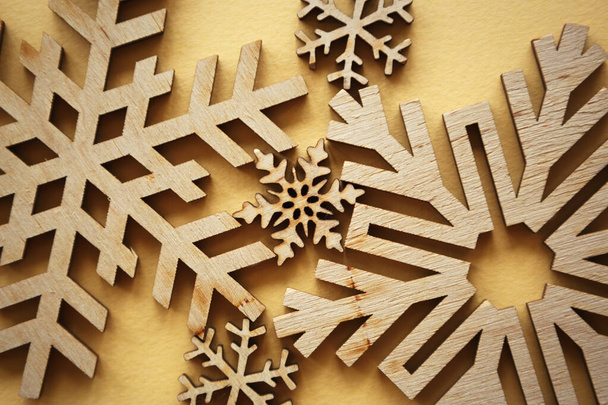 Handmade snowflakes on yellow background.Hand crafted snow flake figures cut from wood for home decor on winter holidays - Fotoğraf, Görsel