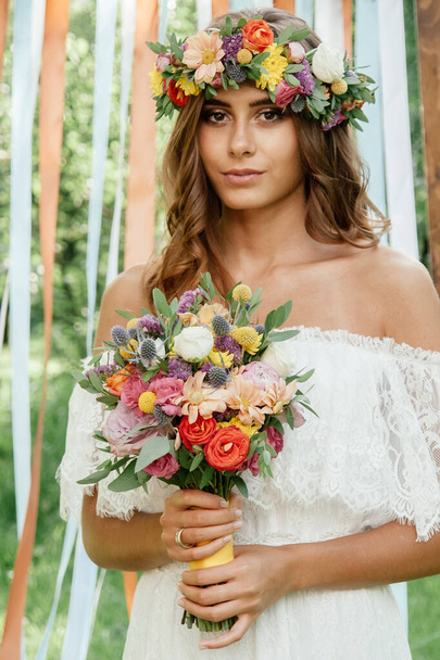 Bella sposa tenuta bouquet di fiori di nozze in mano all'aperto
 - Foto, immagini
