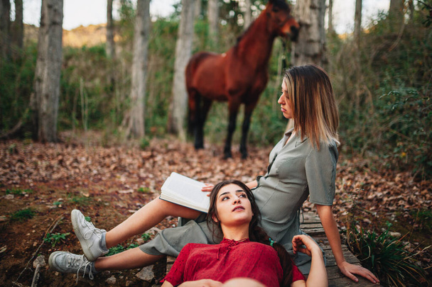 Jovens mulheres lendo um livro e tirando fotos na floresta
 - Foto, Imagem