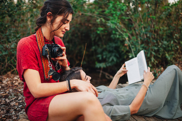 Fiatal nők olvasás egy könyvet, és fotózás az erdőben - Fotó, kép