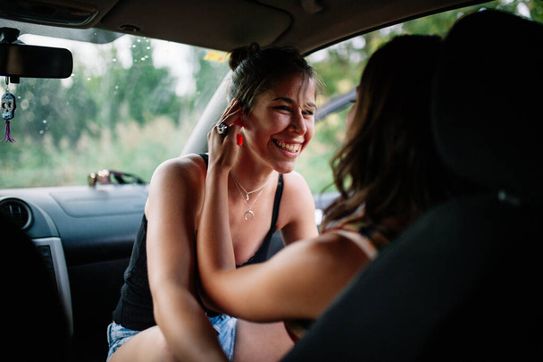 İki genç lezbiyen arabanın içinde eğleniyor. - Fotoğraf, Görsel