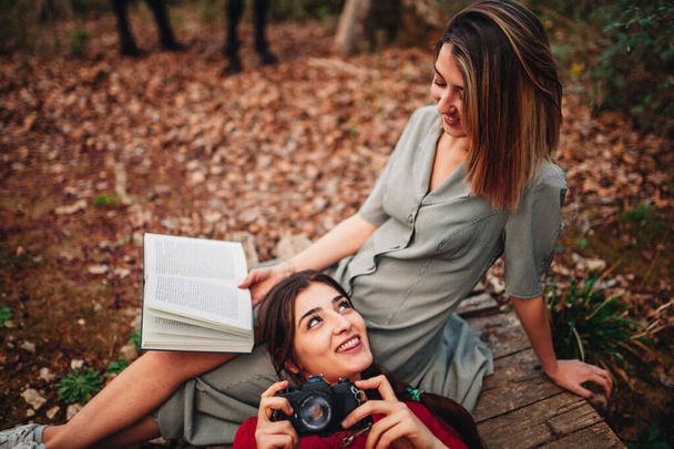 Genç kadınlar kitap okuyor ve ormanda fotoğraf çekiyorlar. - Fotoğraf, Görsel