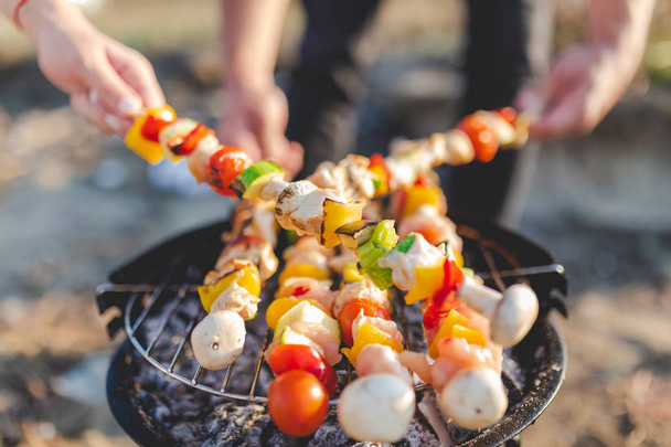 People hands preparing vegetable and meat barbecue in nature. Picnic and food concept. - Foto, afbeelding