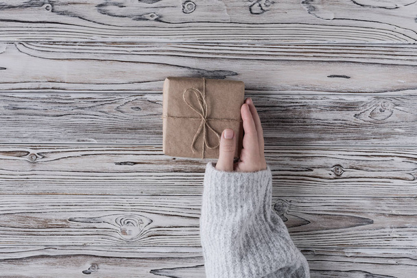 Female packing gifts. Cardboard box in craft paper, christmas rope and tree on the rustic wood planks background. DIY. - Valokuva, kuva
