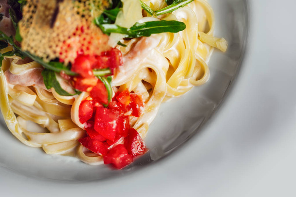 Fettuccinové těstoviny s rajčaty a sýrem na talíři. - Fotografie, Obrázek
