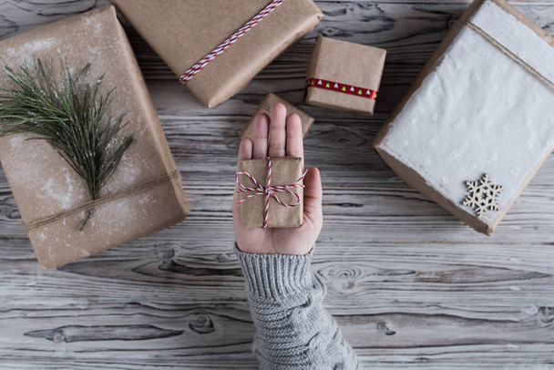 Female packing small gift. Cardboard box in craft paper, christmas rope and tree on the rustic wood planks background. DIY. - Valokuva, kuva