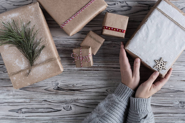 Female packing gifts. Cardboard box in craft paper, christmas rope and tree on the rustic wood planks background. DIY. - Foto, Imagem