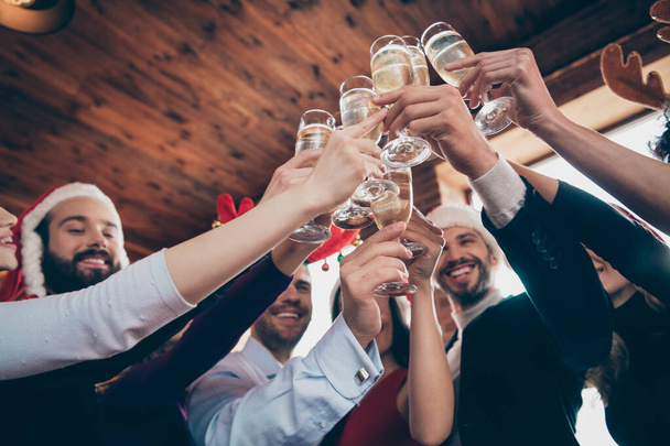 Cropped low angle view photo of fellows group party celebrating corporate company x-mas clinking sparkling wine wear formalwear santa hats restaurant indoors - Fotoğraf, Görsel