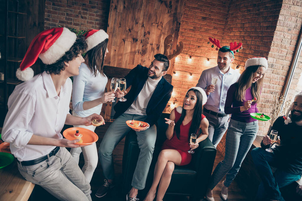 Photo of group x-mas party people friendship communicating clinking wineglasses drink golden wine wear formalwear santa hats deer horns room indoors - Photo, Image