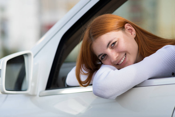 Fiatal, vörös hajú nő, autót vezet. - Fotó, kép