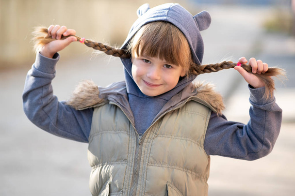 Portrait d'enfant heureux fille avec des tresses de cheveux dans des vêtements chauds en
 - Photo, image