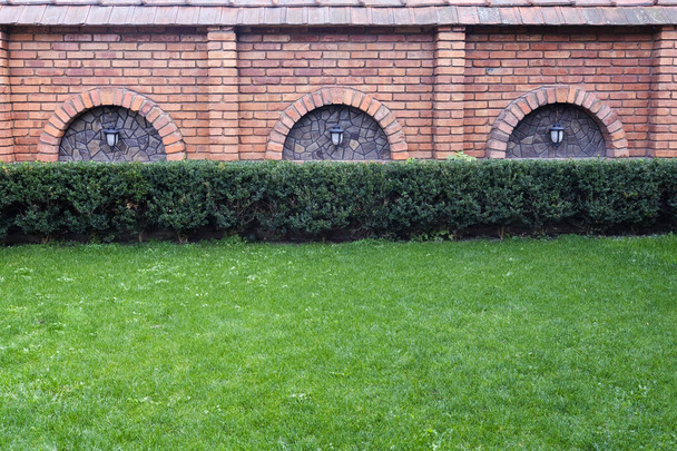 Green lawn leading to an old red brick building - 写真・画像