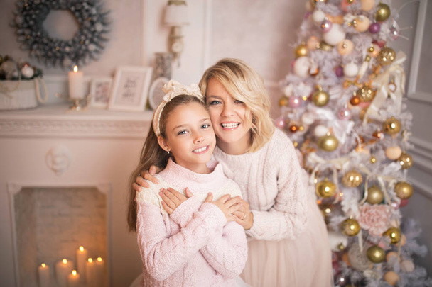 Πορτρέτο μιας χαρούμενης μητέρας και κόρης στο φόντο του εσωτερικού των Χριστουγέννων. - Φωτογραφία, εικόνα