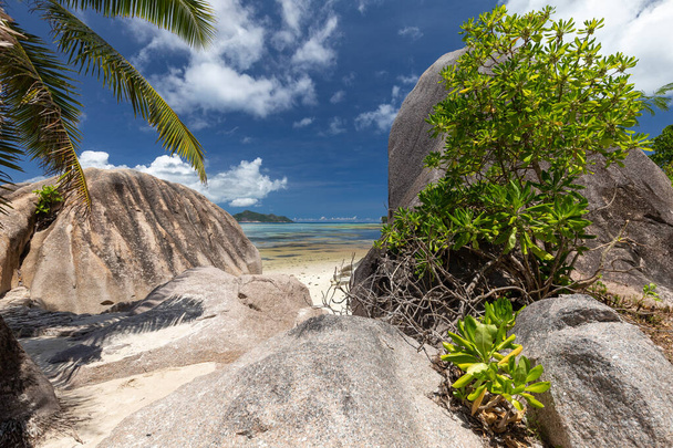 Praia bonita Anse Fonte D 'Argent na ilha de Seychelles La Digue com areia branca, água azul, pedras de granito na praia e céu azul com nuvens brancas
 - Foto, Imagem