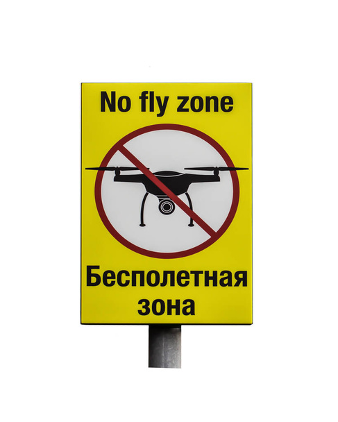 Znak zakazu Strefa zakazu lotów w języku rosyjskim i angielskim. Żółty znak zakazu z wykreśloną sylwetką odizolowanego latającego samolotu - Zdjęcie, obraz