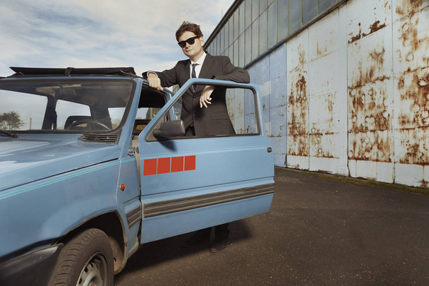 Man in black suit posing with his lovely retro car - Foto, imagen