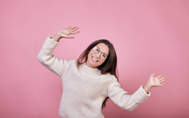 Attractive nice girl in transparent glasses in a knitted sweater posing on pink background  - Fotoğraf, Görsel