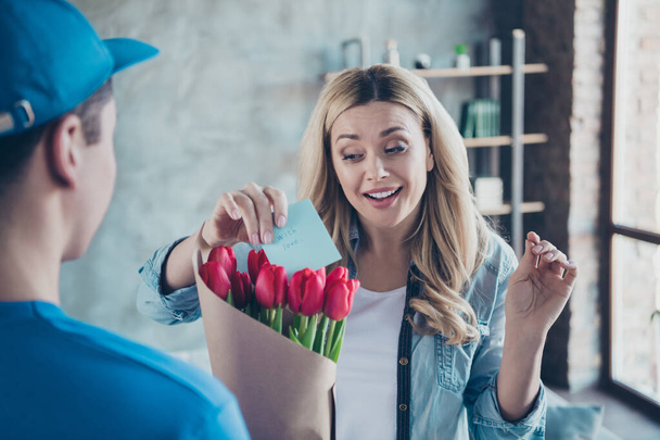 Close-up portrait of nice attractive lovely pretty cheerful cheery wavy-haired girl getting receiving congrats card birthday greetings red flowers at modern industrial loft brick style interior room - 写真・画像