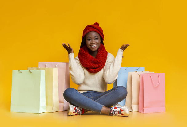 Carefree girl in winter clothes sitting among shopping bags - Fotó, kép