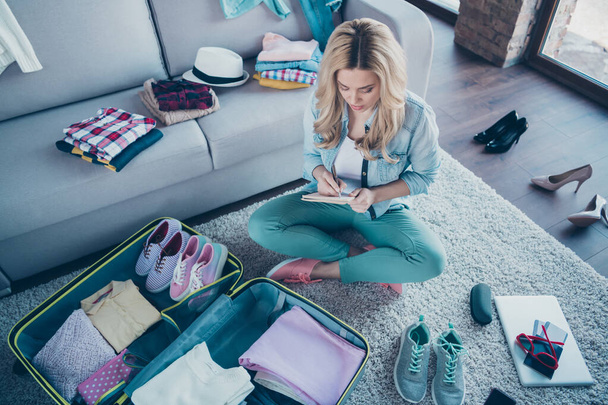 Above high angle view portrait of nice attractive focused wavy-haired girl checking organizing wardrobe clothes wear for air flight relocation voyage at modern industrial loft brick style interior - Φωτογραφία, εικόνα