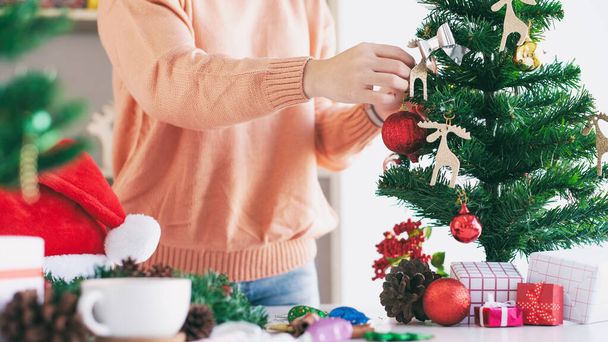 Woman hands decorating the christmas tree and christmas wreath. - Photo, Image