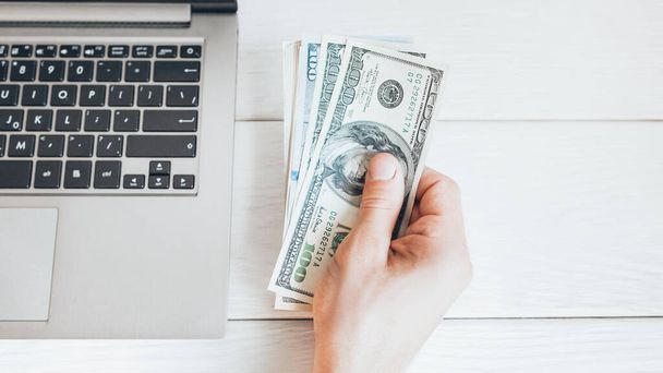 online business hundred dollar bills laptop hand - 写真・画像