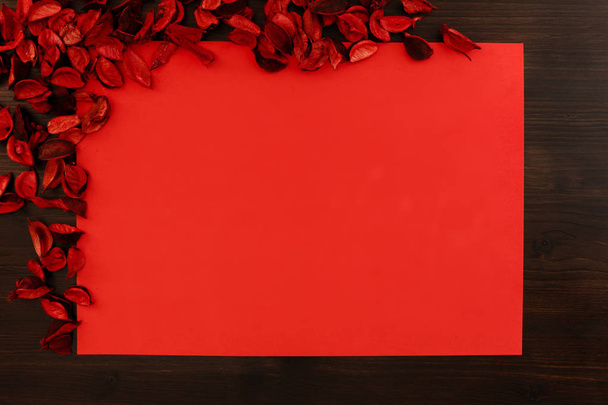 Flat lay vermelho espaço de cópia de Natal com pétalas vermelhas no canto superior esquerdo e madeira escura ao redor
 - Foto, Imagem